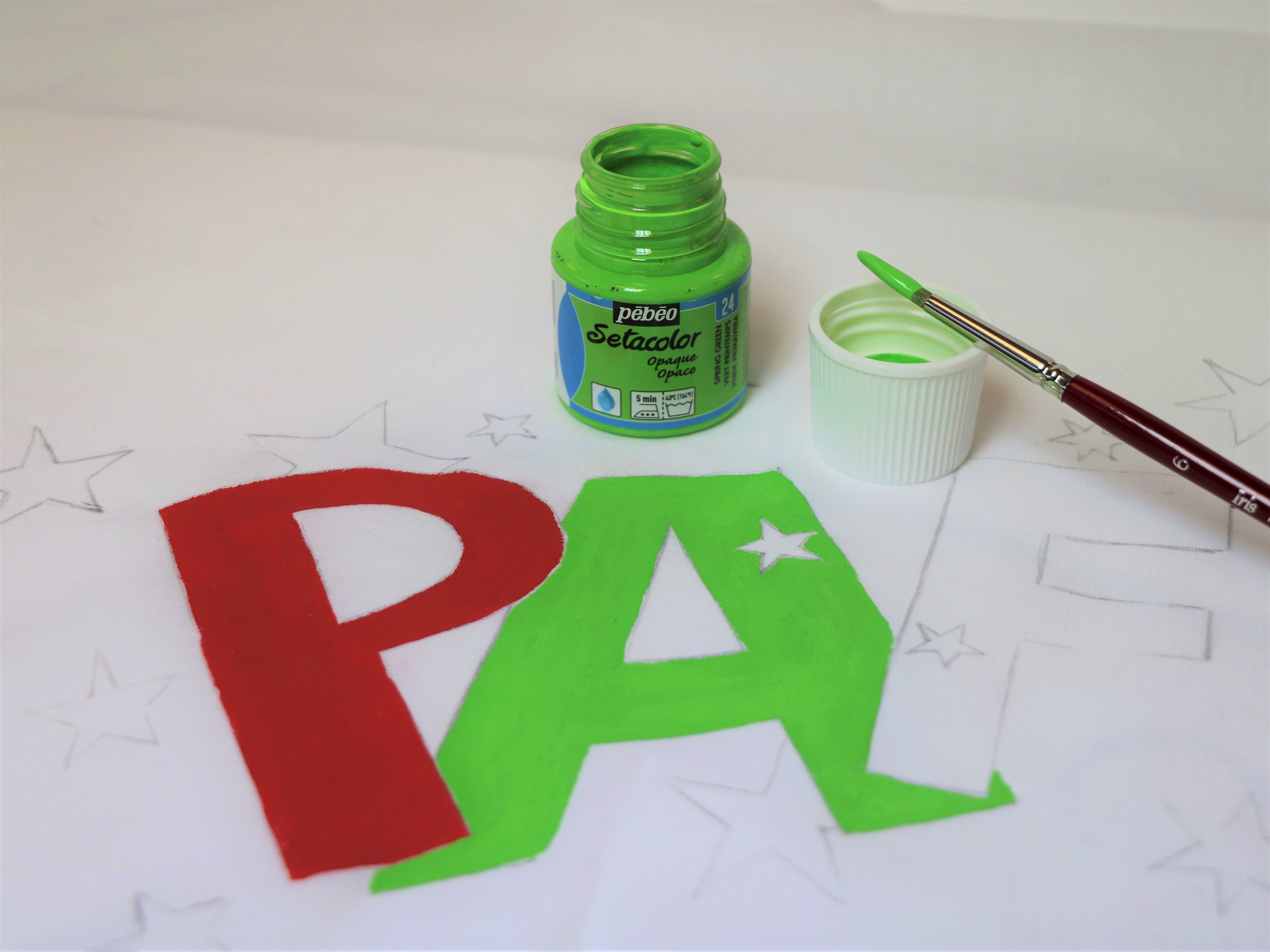 lettres peintes en vert sur coussin blanc