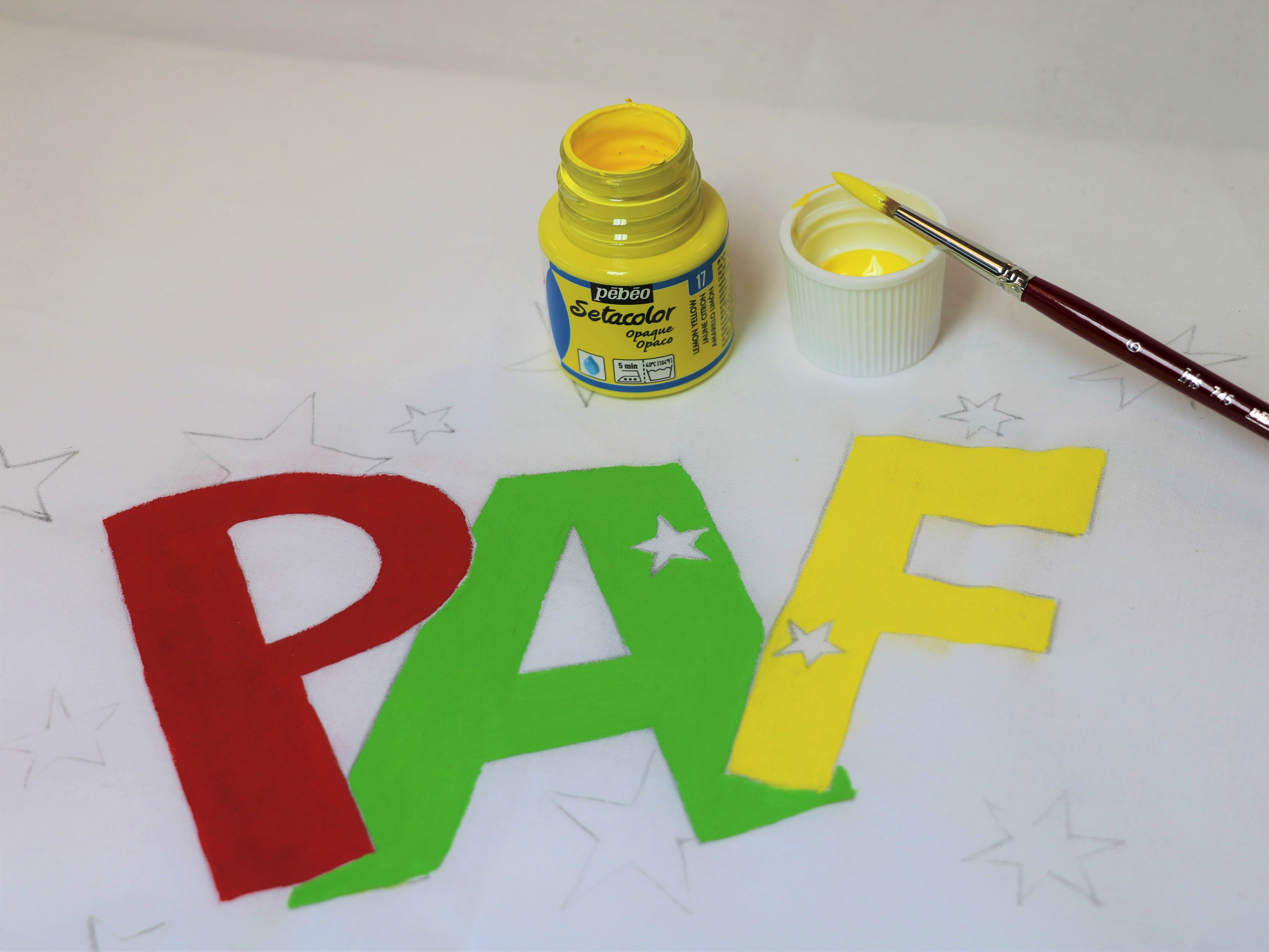 graffiti sur tissu blanc avec la peinture setacolor jaune,